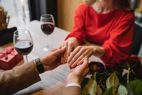 cropped view of woman with engagement ring on finger holding hands with man on valentines day