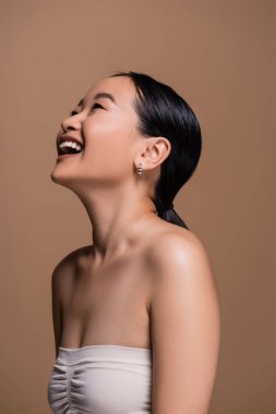 Positive asian model in top looking up isolated on brown 