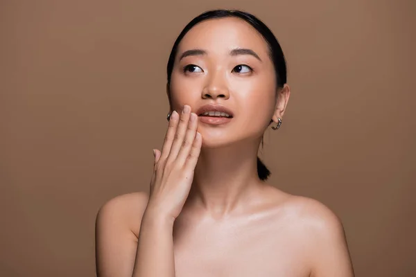 Young Asian Woman Touching Cheek Looking Away Isolated Brown — Stock Photo, Image