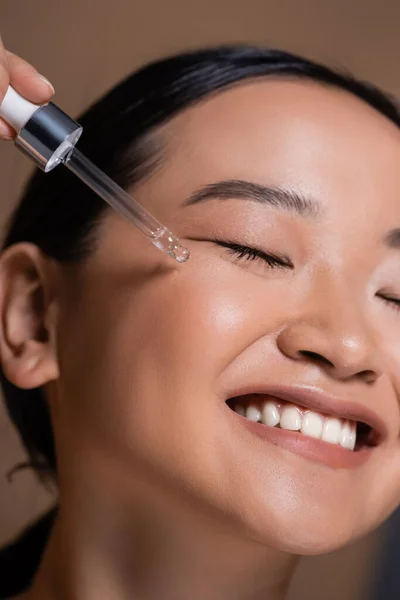 Close View Smiling Asian Woman Applying Cosmetic Serum Face Isolated — Zdjęcie stockowe