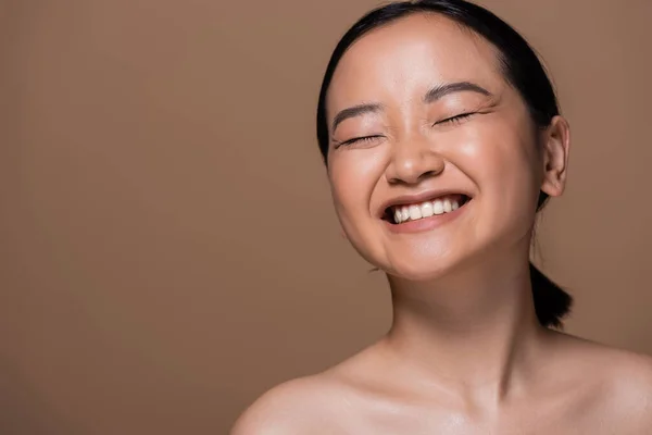 stock image Happy asian woman with naked shoulders and closed eyes standing isolated on brown 
