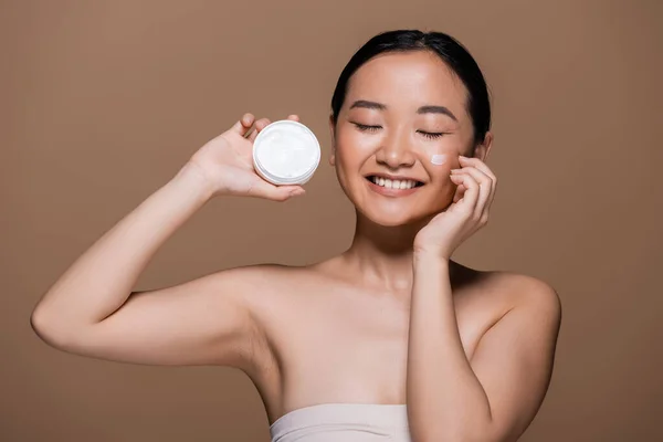Positive Asian Woman Naked Shoulders Holding Face Cream Isolated Brown — Stock Photo, Image