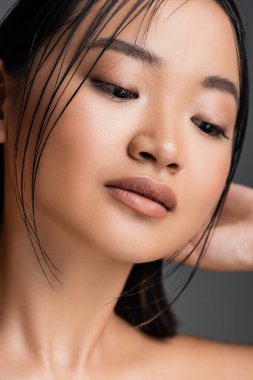 close up portrait of young asian woman with natural makeup posing isolated on grey