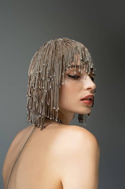 portrait of young woman with metallic jewelry headwear posing isolated on grey 