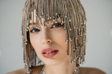 Portrait of young woman in jewelry headwear posing isolated on grey 