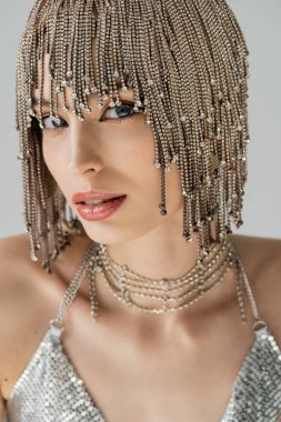 Fashionable model in jewelry headwear standing isolated on grey 