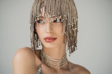 Pretty young model with naked shoulders and rhinestones on headwear isolated on grey 