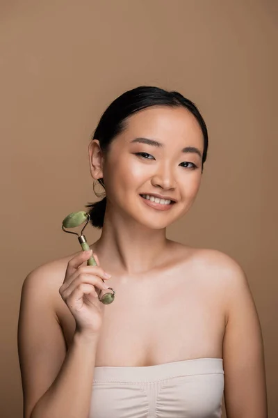 Positive Asian Model Beige Top Holding Jade Roller Looking Camera —  Fotos de Stock