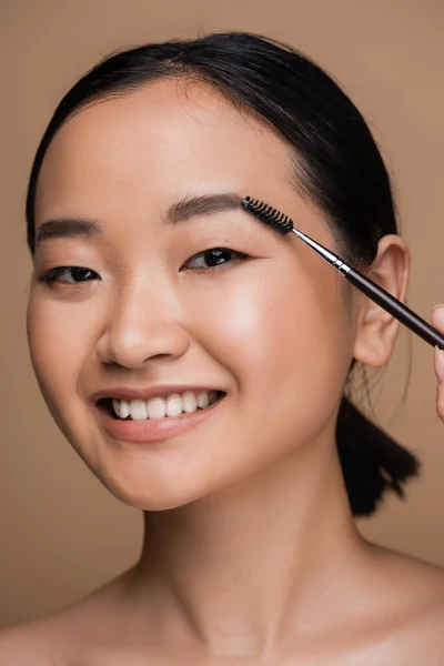 Pretty Asian Model Styling Eyebrow While Holding Brush Isolated Brown — Zdjęcie stockowe