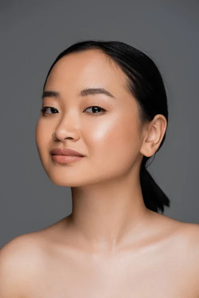 stock image Young asian woman with naked shoulders looking at camera isolated on grey 