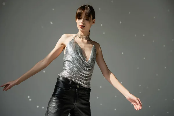 stock image stylish woman in trendy top and leather pants gesturing while standing on grey background 