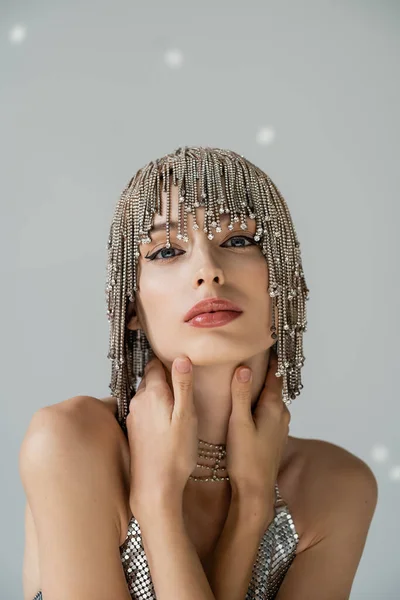 Stock image Portrait of stylish model with visage and jewelry headwear touching neck on grey background with light 