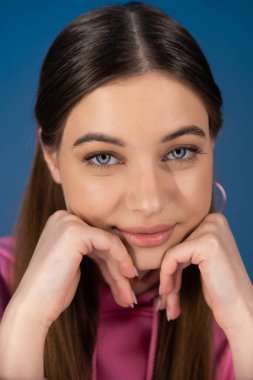 Portrait of teen girl looking at camera isolated on blue 