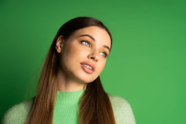 Brunette teenage girl looking away on green background 