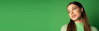 Young brunette teenager looking away on green background with copy space, banner 