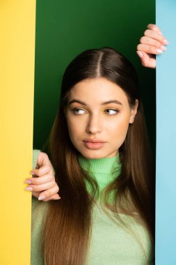 Portrait of teenager in jumper looking away on colorful background 