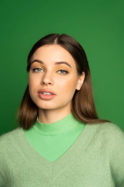 Portrait of pretty teenager in soft jumper looking at camera isolated on green  clipart