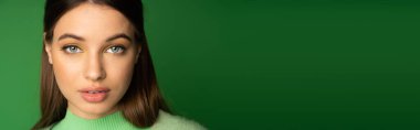 Teen girl with visage looking at camera isolated on green with copy space, banner 
