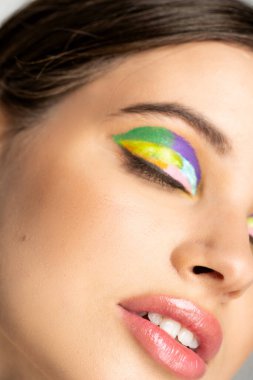 Cropped view of teenage model with colorful visage and closed eyes 