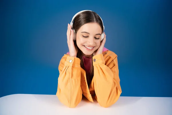 Smiling Teen Girl Listening Music Headphones Table Isolated Blue — Foto Stock