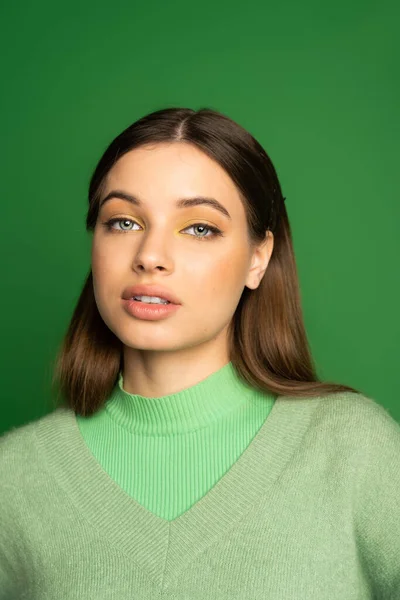 Portrait of pretty teenager in soft jumper looking at camera isolated on green 