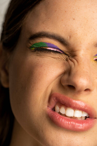 Cropped view of teenage girl with bright visage grimacing isolated on grey 