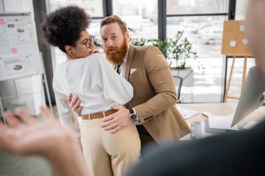 shocked african american woman getting caught by husband while cheating with bearded colleague in office