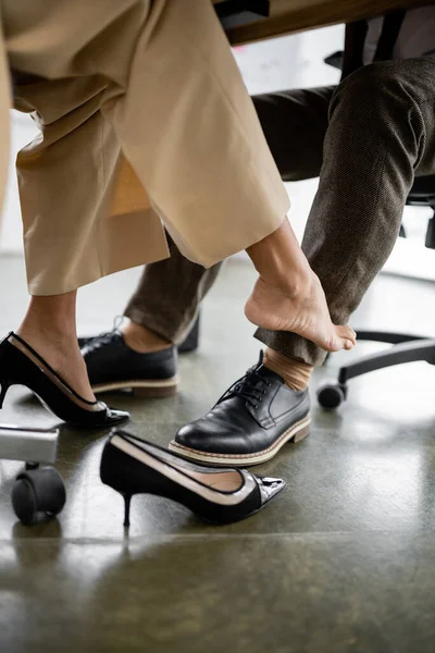 stock image partial view of young african american woman seducing businessman under office desk 