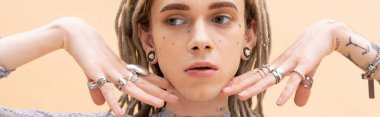 Nonbinary person with dreadlocks and rings on fingers isolated on yellow, banner 