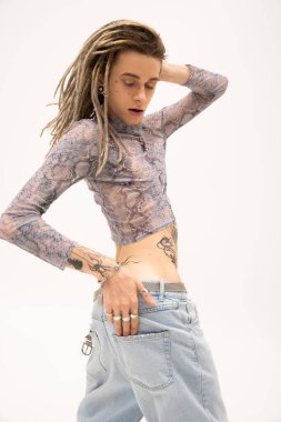 Trendy queer person in jeans and crop top with animal print posing isolated on white 