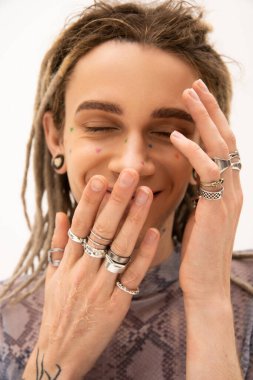 Smiling tattooed queer person with silver rings isolated on white 