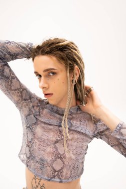 Young tattooed queer person with dreadlocks looking at camera isolated on white 