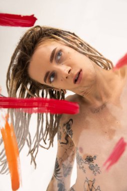 shirtless nonbinary person with dreadlocks posing near red and orange paint strokes on white background clipart