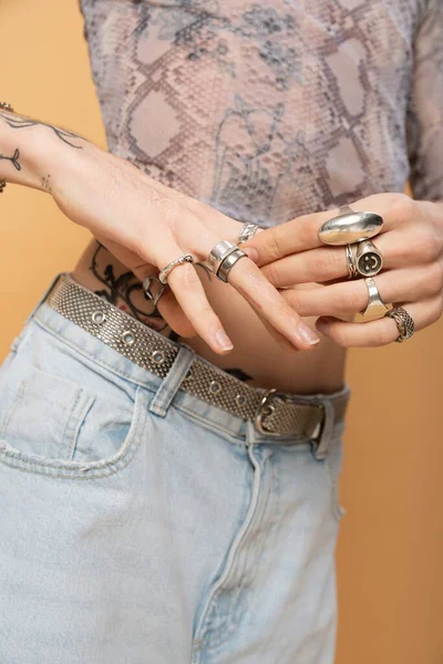 Cropped view of queer person touching rings on fingers isolated on yellow 