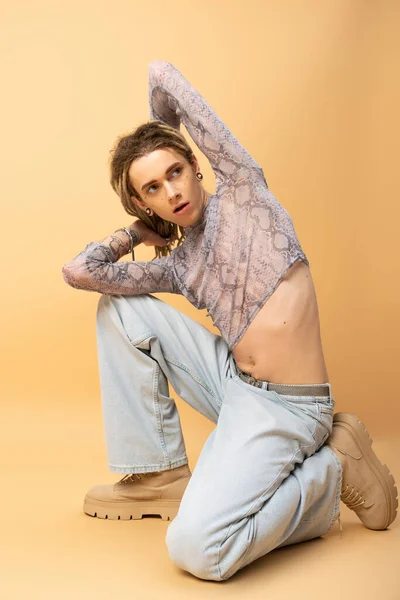 stock image Full length of stylish nonbinary person in jeans and boots posing on yellow background 