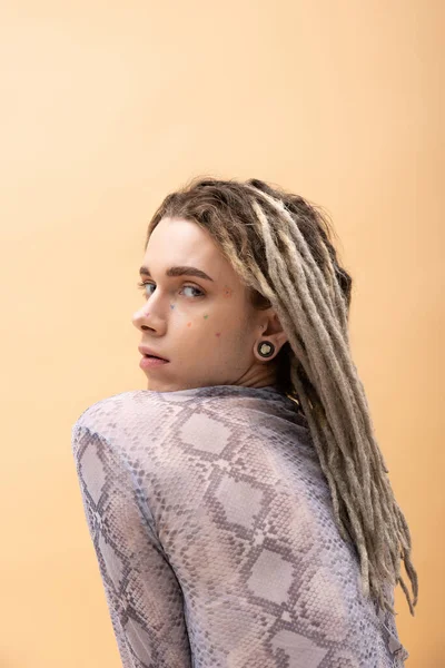 Queer person with dreadlocks looking at camera isolated on yellow 