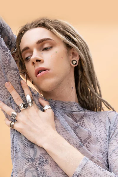 Stylish nonbinary person posing and looking away isolated on yellow 