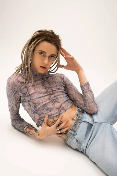 Stylish nonbinary person posing and looking at camera on white background