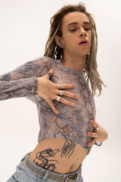 Young queer person touching crop top with animal print isolated on white 
