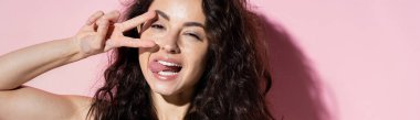 Freckled woman showing peace sign on pink background, banner 