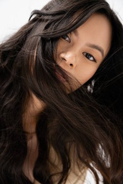 portrait of asian woman with shiny brunette hair looking at camera isolated on white clipart