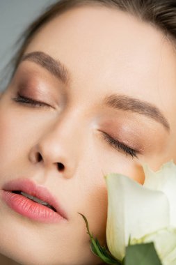 close up portrait of young woman with closed eyes near fresh rose