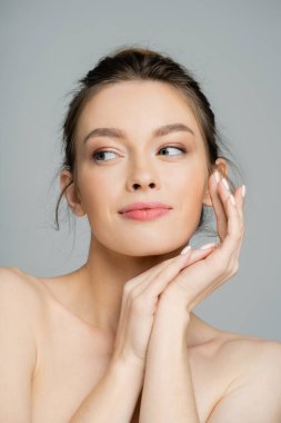 Young woman with natural visage posing and looking away isolated on grey 