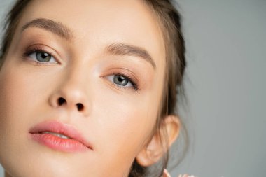 Close up view of young model looking at camera isolated on grey 