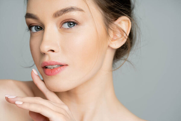 Portrait of young woman with natural visage posing isolated on grey 