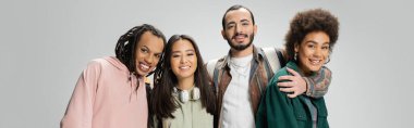 happy multicultural friends in trendy clothes smiling at camera isolated on grey, banner clipart