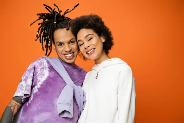 stock image happy african american woman looking at camera near stylish friend with dreadlocks isolated on orange