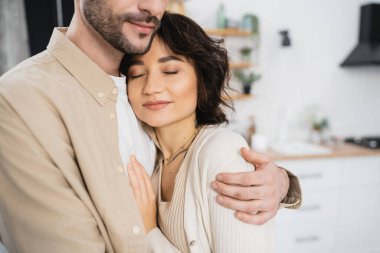 Man hugging smiling brunette woman at home 