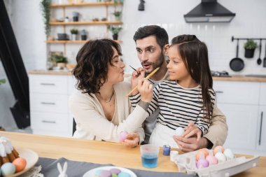 Aile, Easer yumurtalarının yanında boya fırçası ve mutfakta boya tutuyor. 