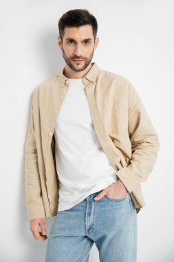 Brunette man in casual clothes posing and looking at camera on white background 